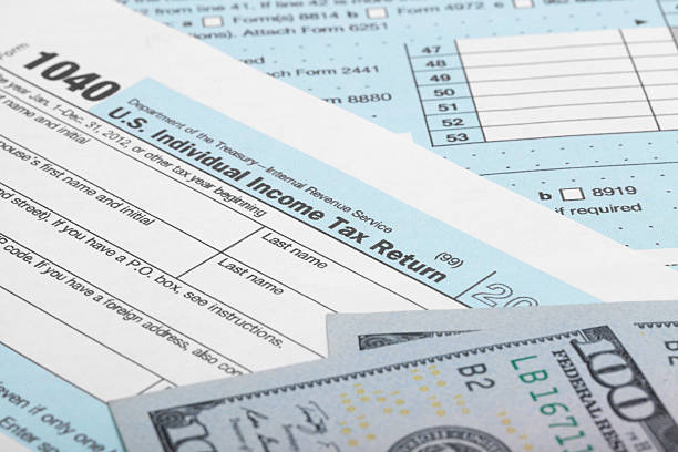istock US Tax Form 1040 with 100 US dollar bills 526597305