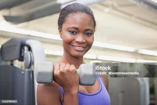 Fit Woman Smiling At Camera Holding Dumbbell Stock Photo - Download Image Now - Dumbbell, Women, 18-19 Years