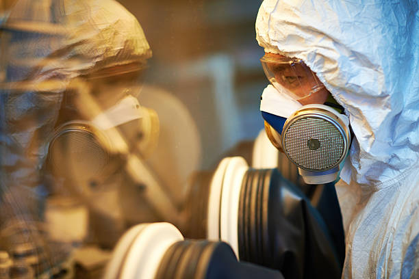 Using glove box Technician wearing protective mask and eyewear looking through glove box glove box stock pictures, royalty-free photos & images