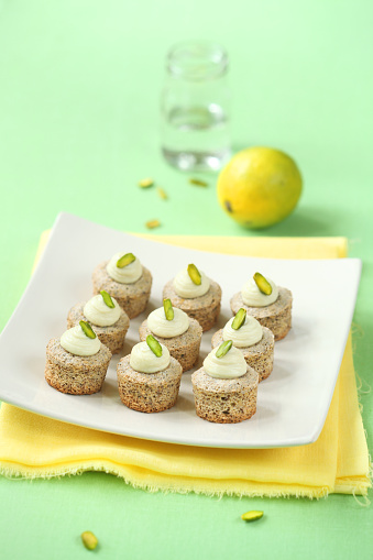 Pistachio Mini Cupcakes with Lime on a square white plate and yellow napkin, on a light green background.