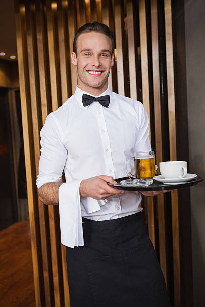 istock Smiling waiter holding tray with coffee and beer 526638443