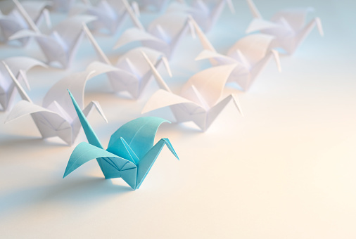 Group of origami birds flying to the light