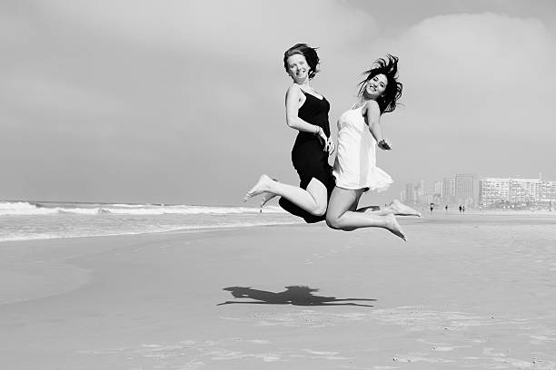 istock two smiling girlfriends jumping at the beach 526654469