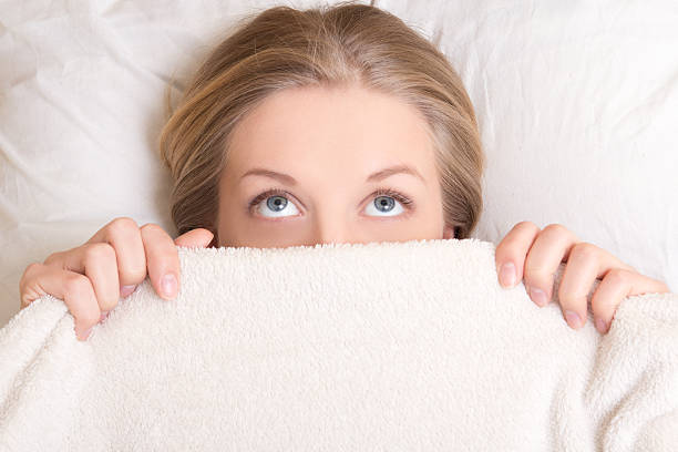 забавная молодая женщина, лежа в постели под одеяло и dreaming - directly below looking women human head стоковые фото и изображения