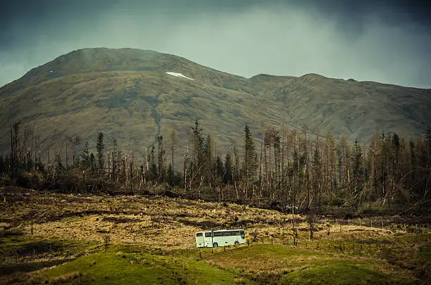 A white coach travelling across the countryside of The Highlands region, Scotland, UK.