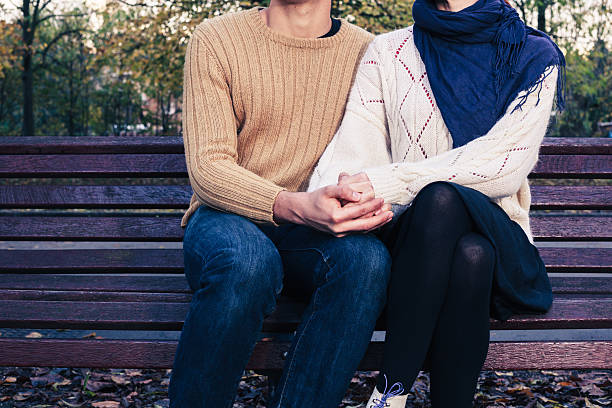 istock Young couple sitting on park bench 526656479