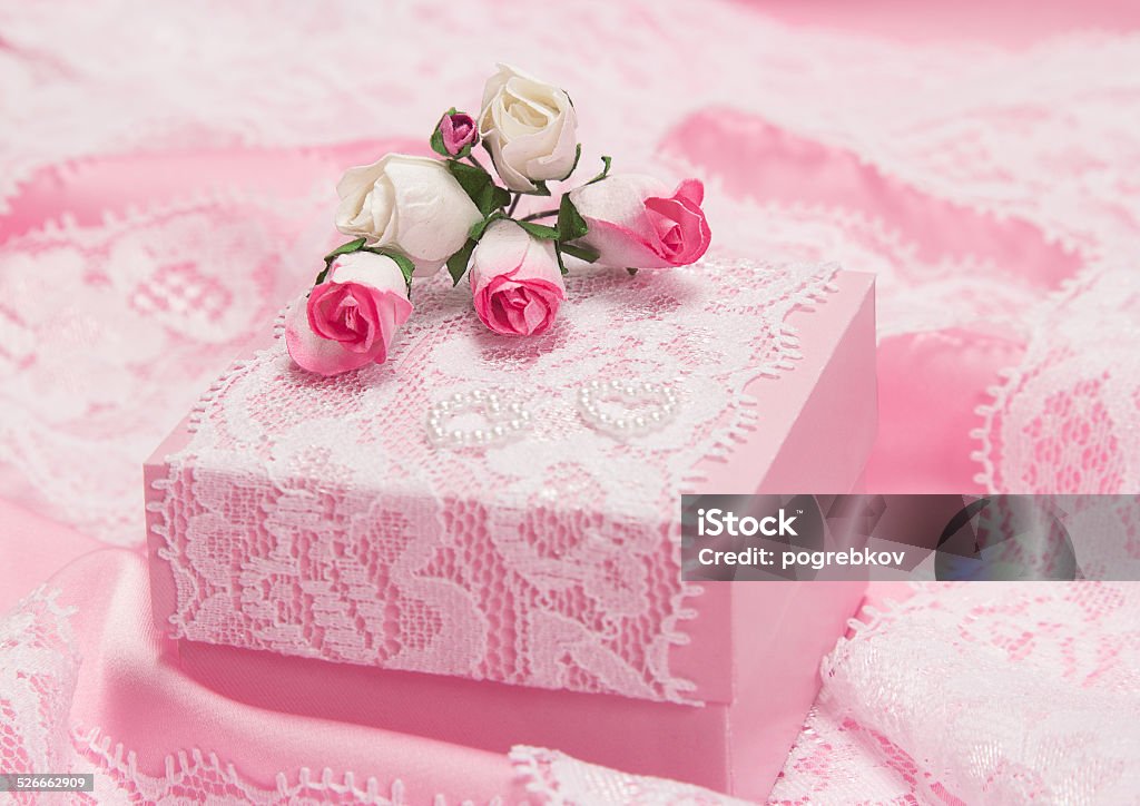 Romantic gift for woman Romantic gift for woman: pink gift box decorated with white lace, paper roses and small hearts made of beads on satin fabric. Shallow depth of field Adult Stock Photo