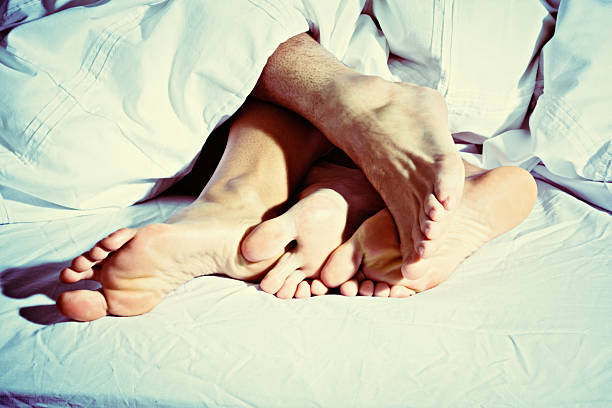 cuddling のカバーアップには、4 つの素足にベッド - bed couple human foot heterosexual couple ストックフォトと画像