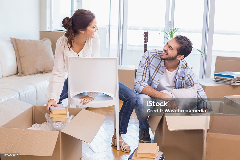 Cute couple unpacking cardboard boxes Cute couple unpacking cardboard boxes in their new home 20-24 Years Stock Photo
