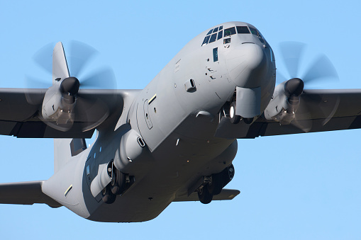 Lockhhed C-130 Hercules Military Transport aircraft taking off against a blue sky
