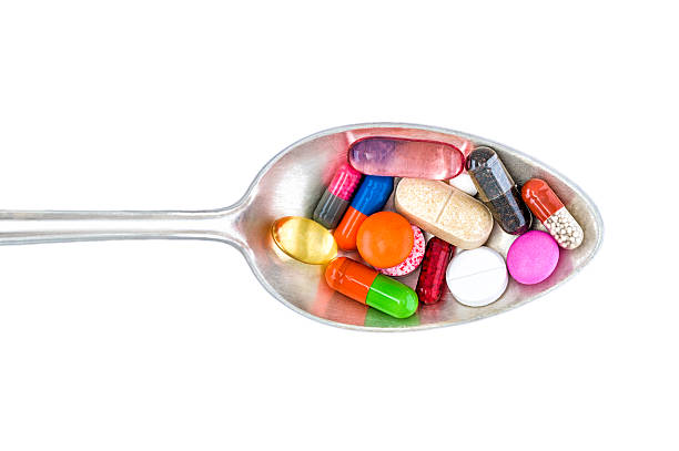 vista superior de colorido pastillas sobre la cuchara. fondo blanco. - vitamin pill nutritional supplement capsule lecithin fotografías e imágenes de stock