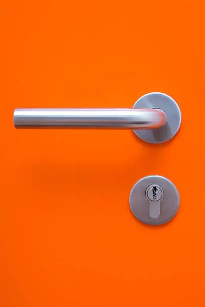 Photo of the part of orange door with metal handle