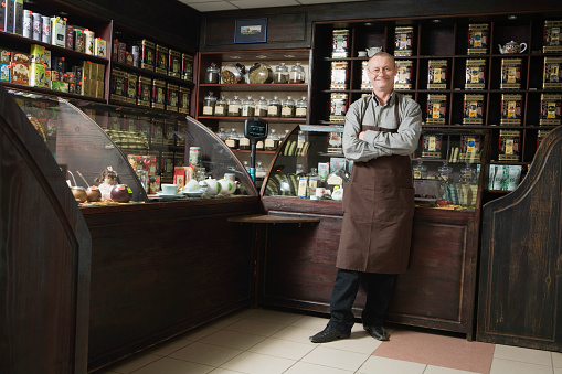 Full length portrait of senior male owner standing in shop