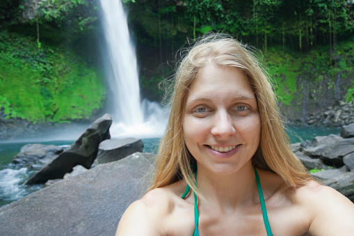 Selfy of a blond woman in front of a waterfall - Catarata Rio Fortuna, La Fortuna, Alajuela province, Costa Rica