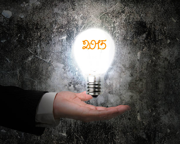 istock hand holding 2015 light bulb illuminated dark old concrete wall 526689947