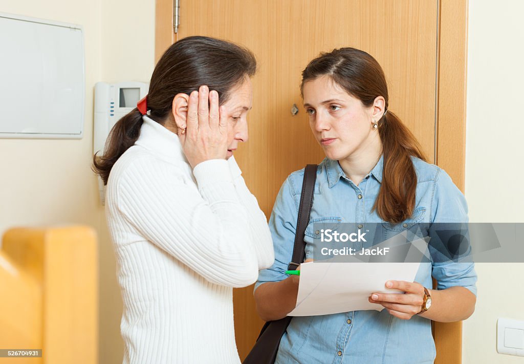 businesswoman trying to collect arrearages from woman businesswoman trying to collect arrearages from woman at home Adult Stock Photo