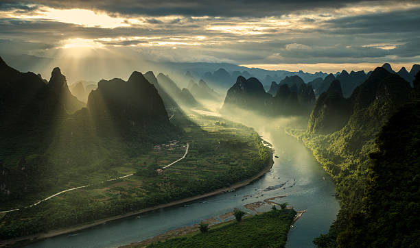 Karst mountains and river Li in Guilin/Guangxi region of China Sun beams on a misty morning on karst mountains and river Li in Guilin/Guangxi region of China karst formation photos stock pictures, royalty-free photos & images