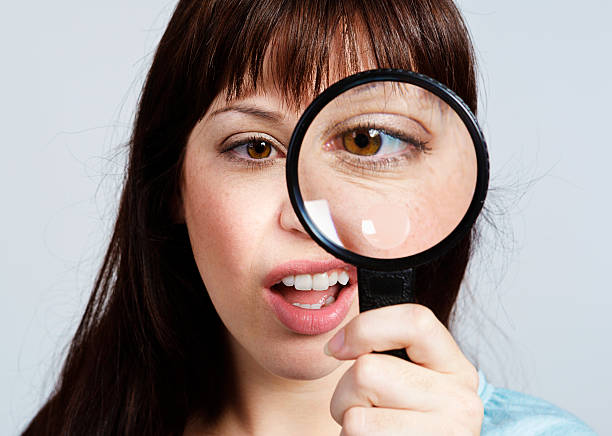 istock What is that? Young woman looks through magnifying glass unhappily. 526705921