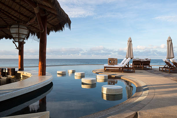 Nobody seat at the wooden stool at the restaurant open air at noon near by a pool. Outdoor cafe with table and old wooden chairs at sunset beside the pool.