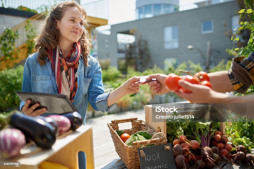 Sympathique femme répondant une cabine de légumes biologiques sur un agriculteur - Photo de Communauté libre de droits