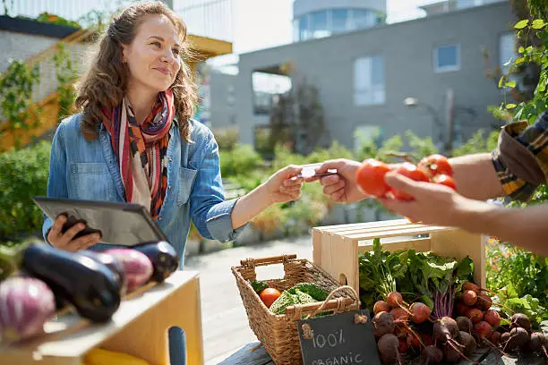 Photo of Friendly woman tending an organic vegetable stall at a farmer