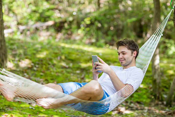istock Mid-adult man using a smartphone in a hammock 526718188