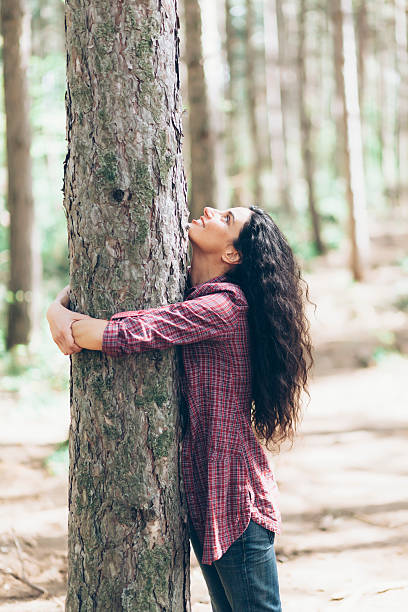 istock Young woman embracing a tree in sunny forest-close up 526721362