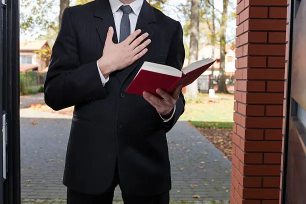 Jehovah's witness standing at the door and holding Bible