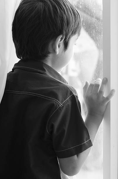 istock Little boy standing behind the door black and white 526722233