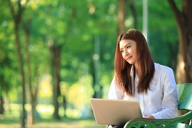 istock beautiful asian woman using laptop computer in the park 526722235