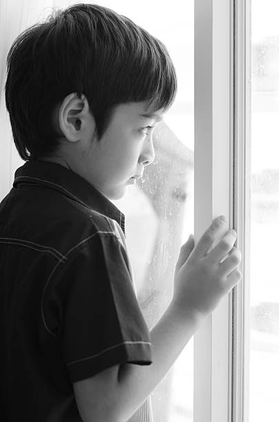 istock Little boy standing behind the door black and white 526722247
