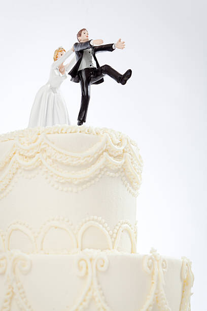 Humorous Bride Chasing Groom Wedding Cake Topper Figurines on White Humorous wedding cake toppers, with the bride chasing and catching the terrified groom who is escaping, running from getting married. A fun bridal shower, renewed vows, or destination wedding reception joke for newlyweds or marriage anniversary couples. Frosted dessert with husband and wife figurines on a white background, with copy space. scary bride stock pictures, royalty-free photos & images