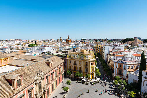 Seville, Spain - September 20, 2015: Aerial view of the ancient city of Seville in Spain on a clear day, with the Plaza Virgen de los Reyes and the baroque facade of the Palacio Arzobispal in the foreground.