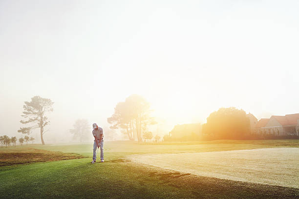 chip shot golf Golfer chipping onto the green at sunrise on the golf course in misty conditions mid distance stock pictures, royalty-free photos & images