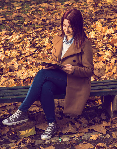 istock Girl sitting on bench in ark and reading a book 526727303