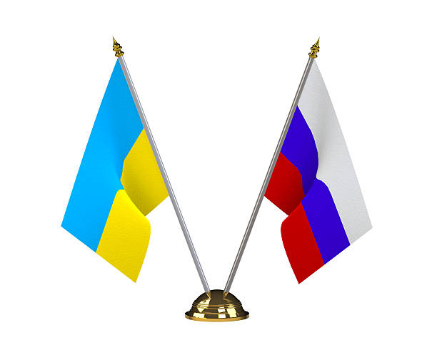 Ukraine and Russia table flags on a golden pedestal isolated on white backgound