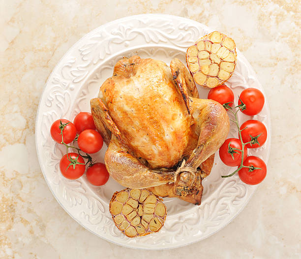 istock whole grilled chicken on a plate with tomatoes and garlic 526728468