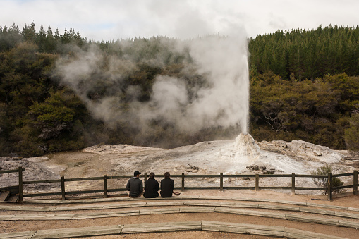 Rotorua, New Zealand - 1 Jun 2013: three men watching Lady Knox geyser near Rotorua in New Zealand