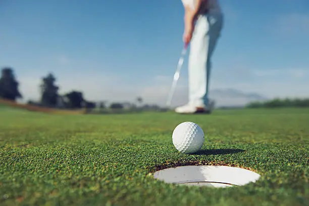 Golf man putting on green for birdie while on vacation