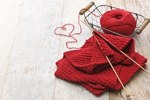 hand knitted red scarf, yarn ball and knitting needles, handmade christmas present