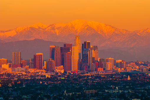 Downtown Los Angeles skyline aerial view with snow capped Mount Baldy / Mount San Antonio (part of the San Gabriel Mountains) during sunset.