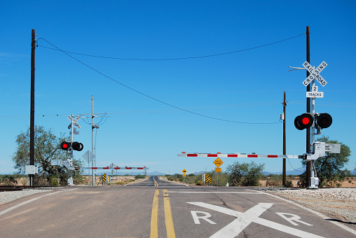 Railroad crossing in a suburban area with the gates down and warning lights blinking before the train passes by