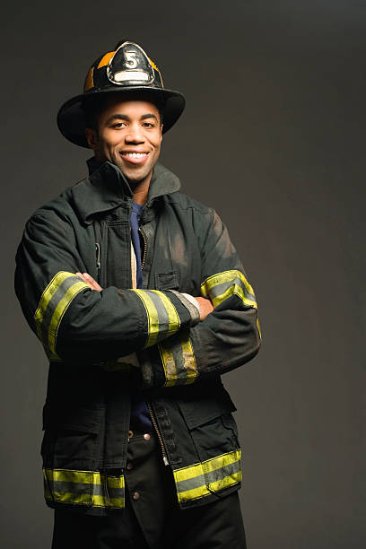 fireman sonriendo sobre fondo negro, vertical - fire department heroes portrait occupation fotografías e imágenes de stock