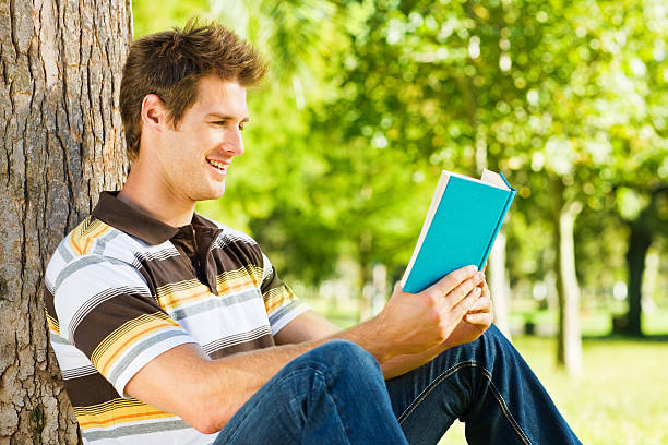 istock Side view of handsome young male reading a blue book 526746399