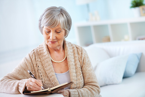 Senior woman making notes in notepad