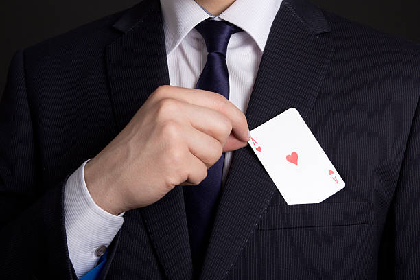 mans hand hiding playing card in suit pocket stock photo