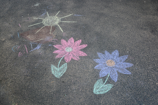 Child's drawing with chalk on asphalt. Sun and flowers