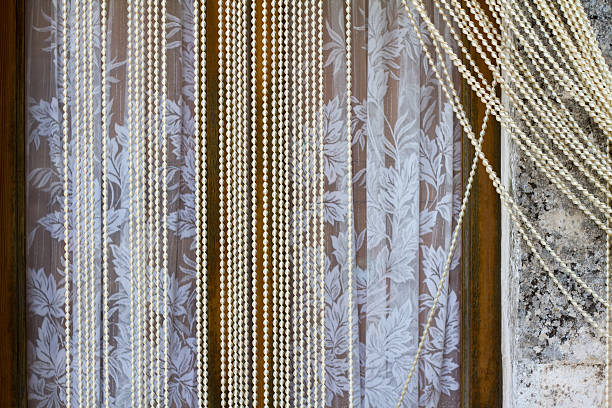 Lace curtains and plastic beads (to keep out flies) hang in windows in Scicli, Sicily.