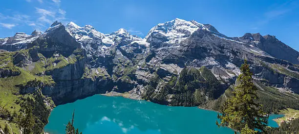 The panorama in summer view over the Oeschinensee (Oeschinen lake) and the alps on the other side near Kandersteg on bernese oberland in Switzerland.