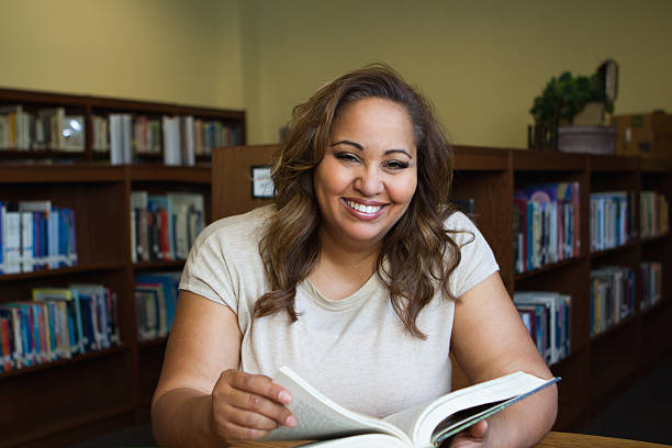 femme lisant un livre dans la bibliothèque - adult student women mature adult library photos et images de collection